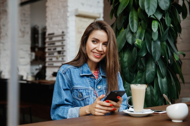 Mulher olhando para o telefone em uma cafeteria