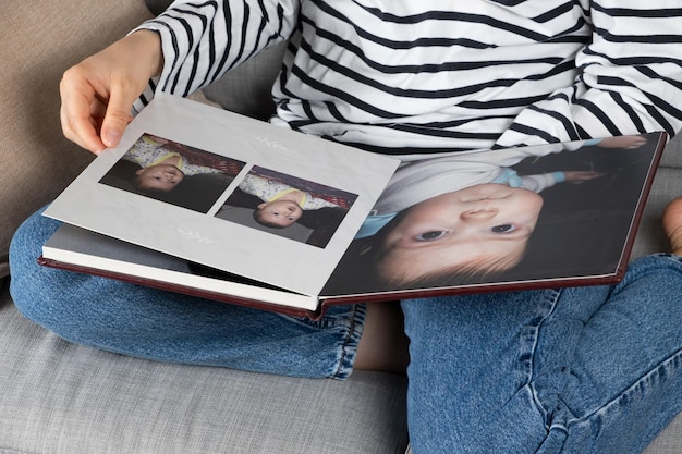 Mulher olhando para um álbum de fotos de família com sua família e um bebê