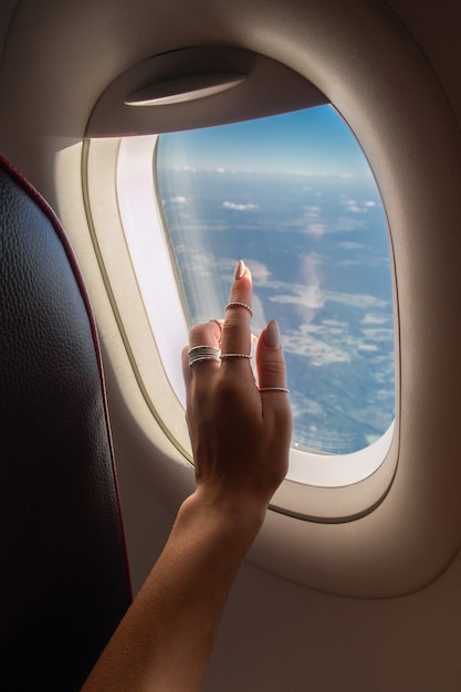 Foto mulher olhando pela janela do avião durante o nascer do sol