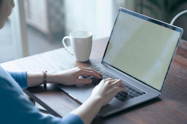 Mulher operando um laptop na mesa da sala