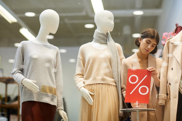 Mulher organizando exibição em loja de roupas