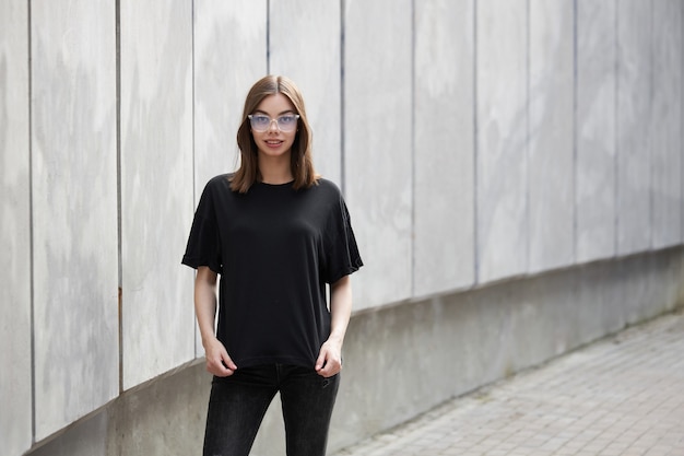 Mulher ou menina vestindo uma camiseta preta de algodão em branco com espaço para seu logotipo, mock up ou design em estilo urbano casual