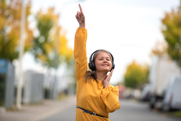 Foto mulher ouvindo música enquanto dança na cidade