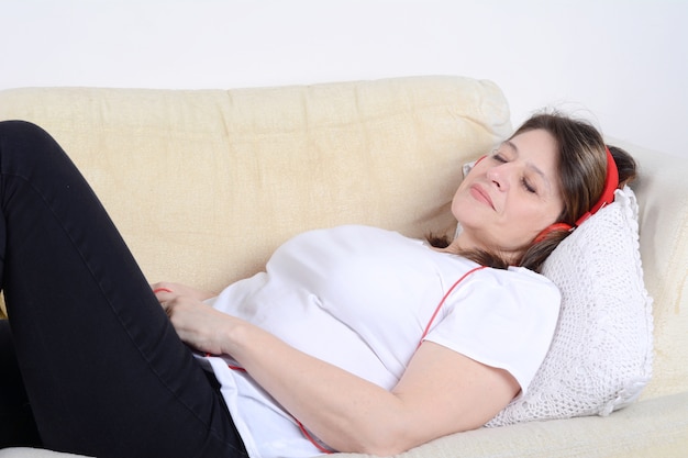 Mulher ouvindo música no sofá.