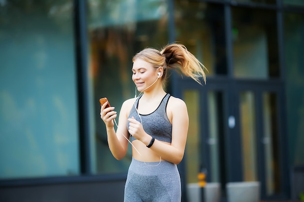 Mulher ouvindo música no telefone enquanto se exercita ao ar livre