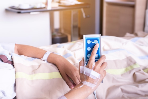 Mulher paciente entrega as mãos usando o controle remoto para ajustar o nível da cama do doente no hospital