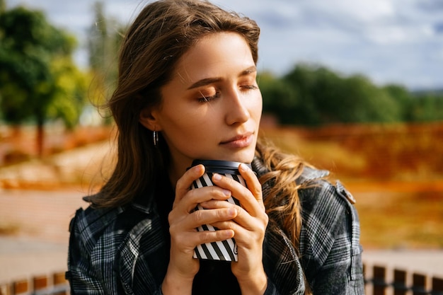 Mulher pacífica está segurando firme sua xícara de café enquanto desfruta da luz do sol