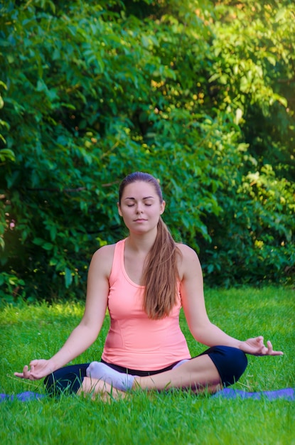 Mulher pacificada em um top rosa fazendo yoga de manhã