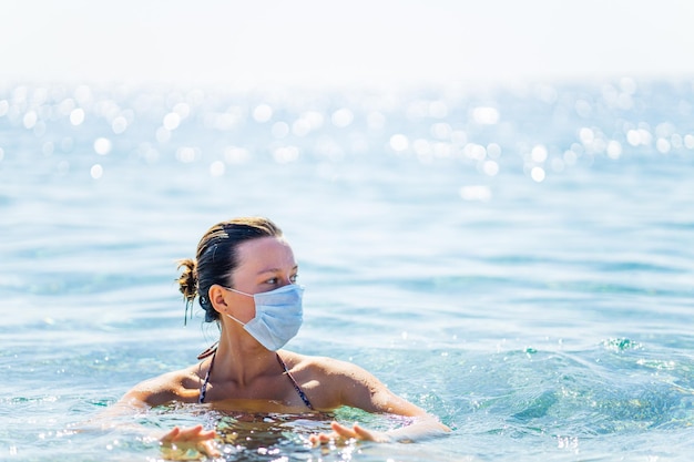 Mulher paranóica nadando na água com máscara no rosto em dia ensolarado