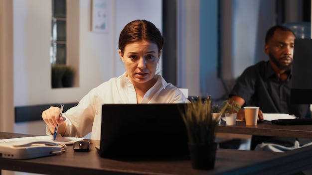 Mulher participando de reunião de videochamada on-line no laptop, conversando com pessoas na webcam com videoconferência remota à noite. Conversando no chat de teleconferência, telecomunicações pela internet.