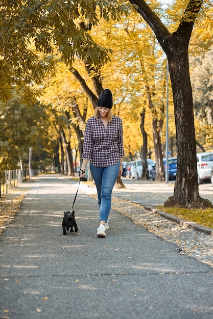 Mulher passeando com Bulldog Francês no outono