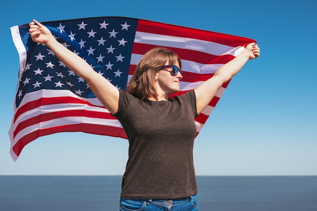 Mulher patriótica com a bandeira americana nas mãos no fundo do mar