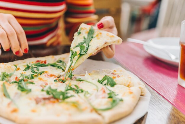 Foto mulher pega um pedaço de pizza de perto foco suave