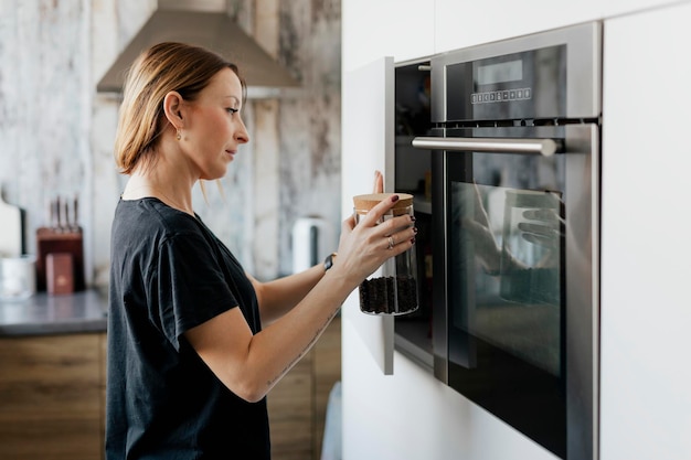 Mulher pega um pote de grãos de café no armário da cozinha