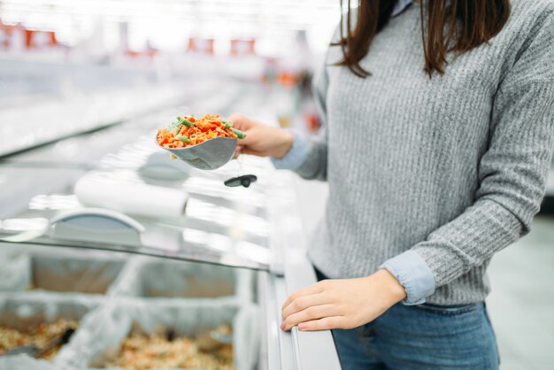 Mulher pegando pacote de vegetais congelados