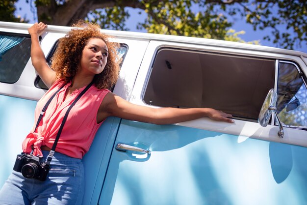 Mulher pensativa, apoiando-se na caravana com câmera