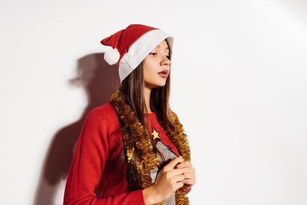 Mulher pensativa com um chapéu de Natal em um fundo cinza