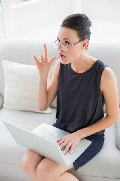 Mulher pensativa e expressiva bem vestida usando laptop