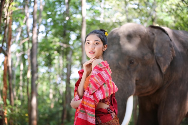 Mulher pensativa em pé com elefante no fundo da floresta