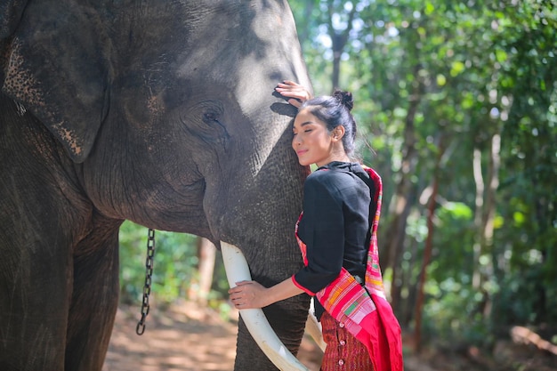 Mulher pensativa em pé com elefante no fundo da floresta