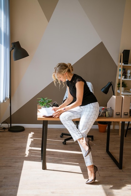 Mulher pensativa no escritório planejando horário de trabalho no notebook sentado