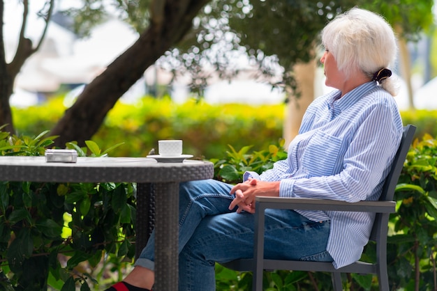 Mulher pensativa relaxando em um pátio externo à mesa de um restaurante