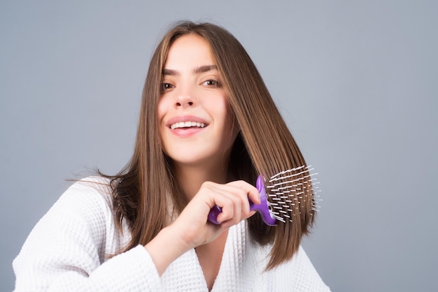 Mulher penteando o retrato do modelo feminino com um pente escovando o cabelo menina com escova de cabelo close-up f