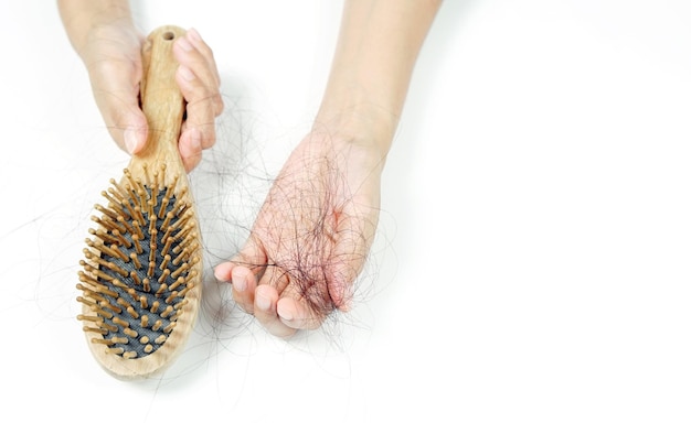 Mulher perdendo cabelo na escova de cabelo na mão.