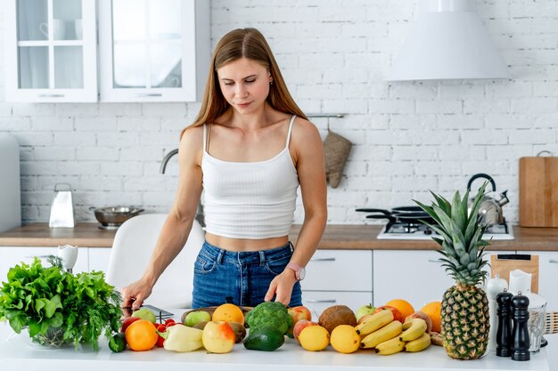 Mulher perto da cozinha com alimentos saudáveis.