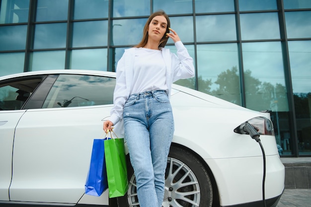 Foto mulher perto de carro elétrico veículo carregado na estação de carregamento