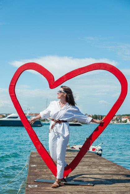 Mulher perto de ponto de foto em forma de coração na praia do mar Croácia Ístria