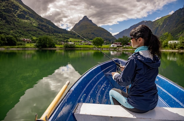 Mulher pescando em um barco. Bela natureza paisagem natural da Noruega. vale de Lodal do lago lovatnet.