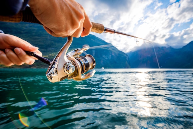 Mulher pescando na vara de pesca na Noruega A pesca na Noruega é uma forma de abraçar o estilo de vida local Inúmeros lagos e rios e uma extensa costa significam oportunidades excepcionais