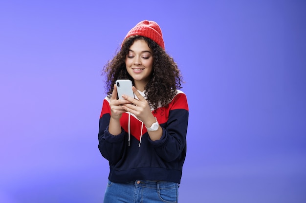 Mulher pesquisando na internet memes engraçados segurando o celular nas mãos, sorrindo com alegria e fofa no s ...