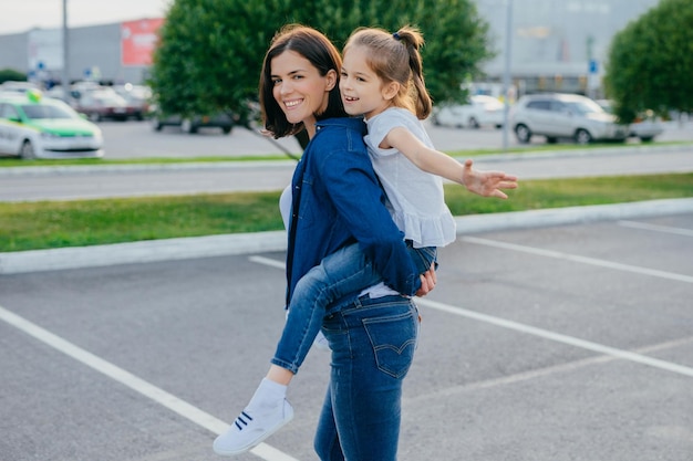 Mulher piggybacking menina enquanto estava na cidade