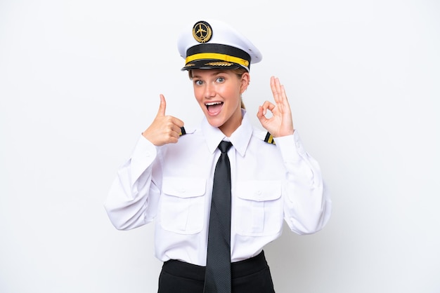 Mulher piloto caucasiana de avião isolada em fundo branco mostrando sinal de ok e polegar para cima gesto