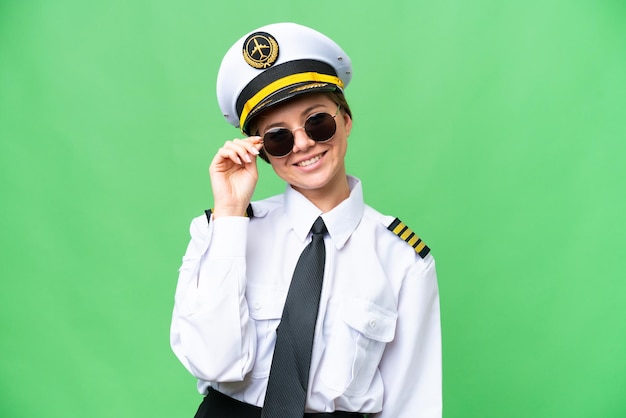 Mulher piloto de avião sobre fundo croma chave isolado com óculos e feliz