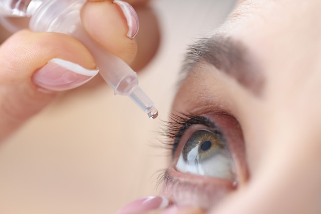 Mulher pingando colírio nos olhos