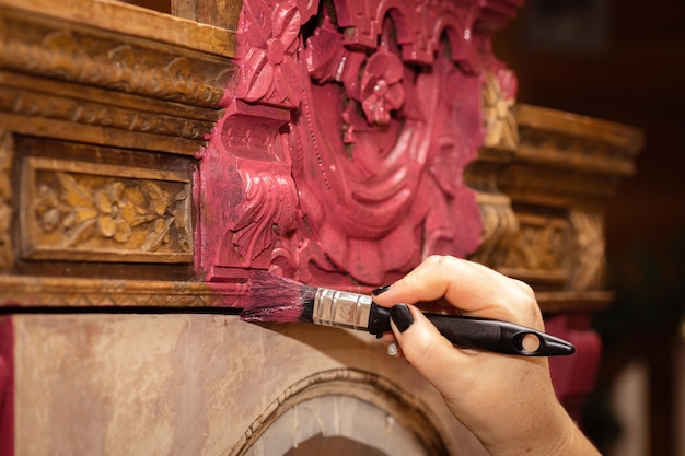 Mulher pintando à mão um armário velho com lindos ornamentos esculpidos nele com pincel reutilização de oficina antiga para restauração de móveis antigos em casa ecofriendly