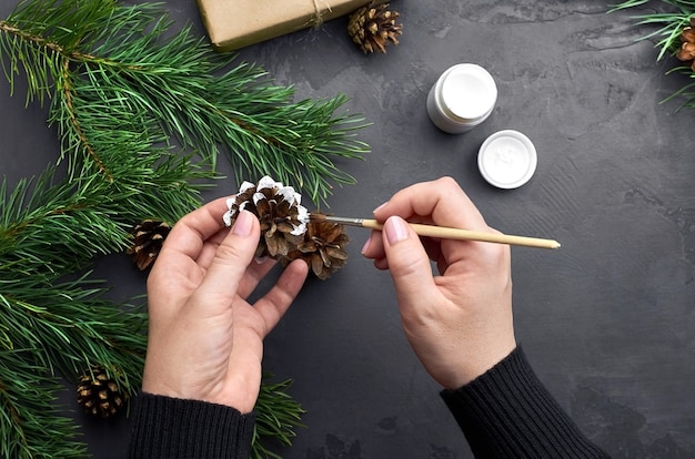 Mulher pintando pinhas para decoração de natal