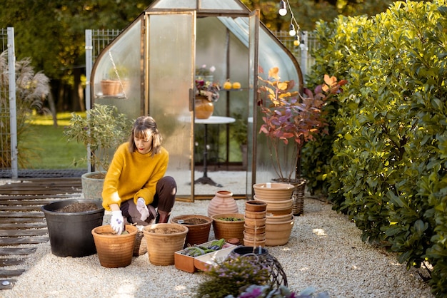 Mulher plantando flores em jarros no jardim