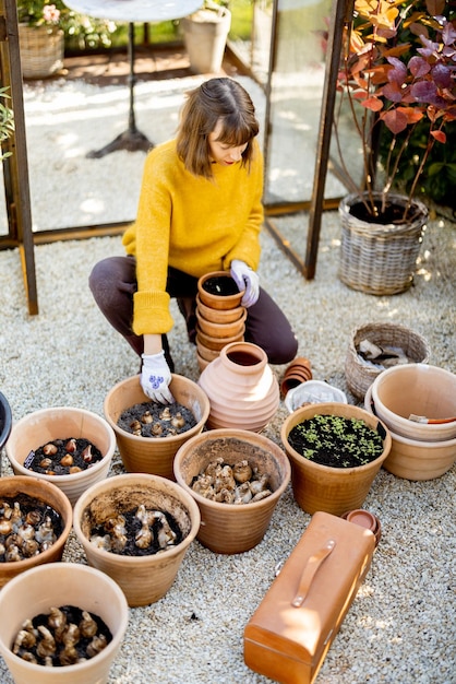 Mulher plantando flores em jarros no jardim