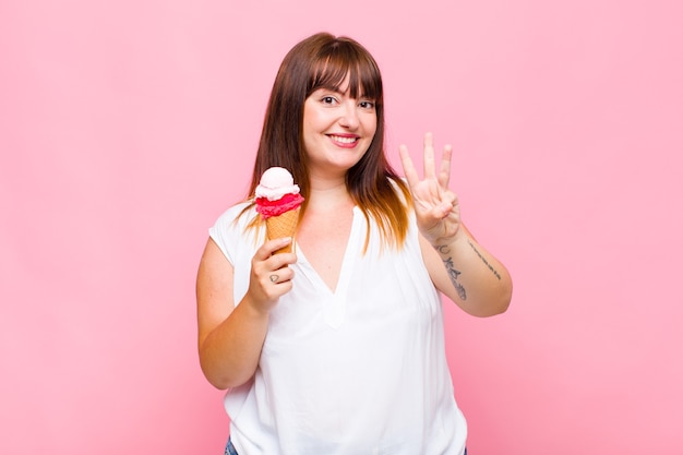 Mulher plus size sorrindo e parecendo amigável, mostrando o número um ou primeiro com a mão para frente, em contagem regressiva