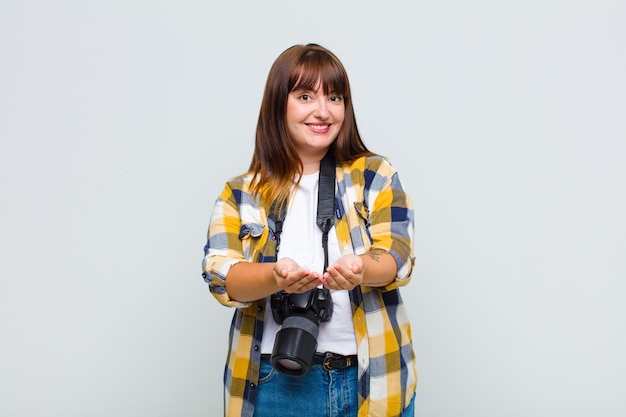 Mulher plus size sorrindo feliz com um olhar amigável, confiante e positivo, oferecendo e mostrando um objeto ou conceito