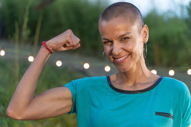 Mulher poderosa com o punho erguido, cabelo rapado e um grande sorriso, mulher confiante e forte.