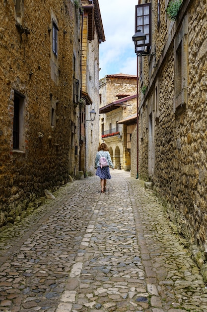 Mulher por trás caminhando por um beco estreito com velhas casas de pedra