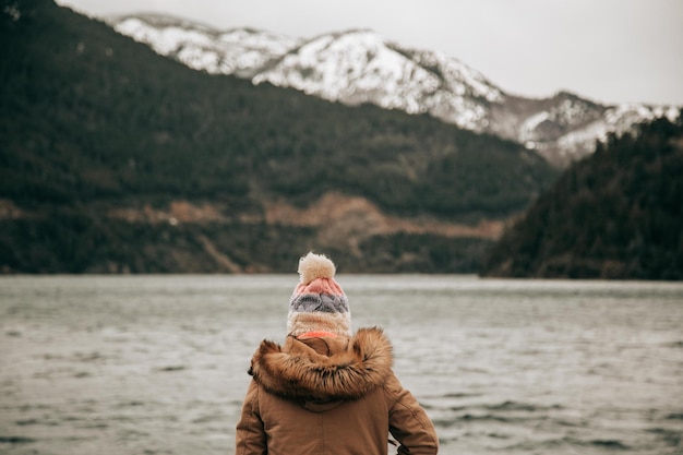 Mulher por trás em um lago com montanhas nevadas