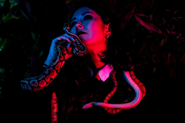 Mulher posando com cobra na parede escura