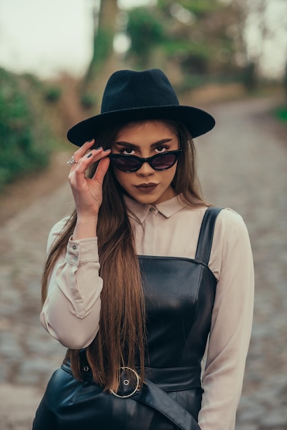 Mulher posando do lado de fora em um vestido e um chapéu