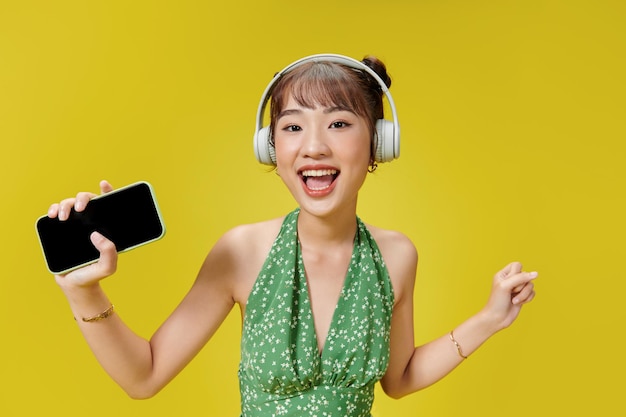 Mulher posando isolada sobre fundo amarelo ouvindo música com fones de ouvido dançando cantando